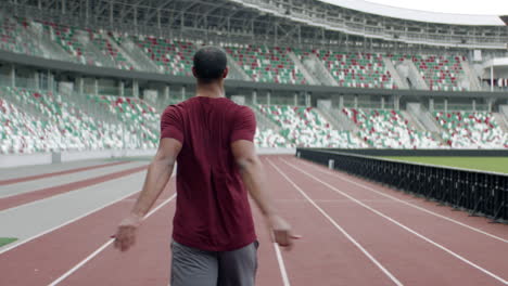 Retrato-De-Un-Hombre-Afroamericano-De-Raza-Negra-Calentándose-Antes-De-Correr-En-Una-Pista-De-Estadio-Vacía-Temprano-En-La-Mañana.-Toma-Tomada-Con-Lente-Anamórfica.